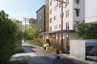 A modern residential complex lines a pathway with greenery, featuring pedestrians and cyclists enjoying the vibrant, urban environment.