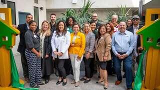 A diverse group of professionals poses together in a welcoming environment, showcasing teamwork and community spirit.