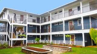 A charming, multi-level building with blue walls, balconies, and landscaped gardens, offering a cozy outdoor space for residents.