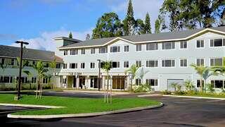 Meheula Vista features a three story affordable housing community by EAH Housing with soft toned exterior, tropical landscaping, and resident parking areas.