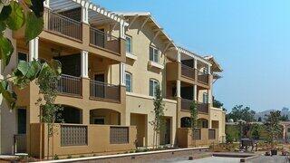 Bella Terra Apartments exterior showcasing a three-story residential community with balconies, stucco facade, and landscaped courtyard.