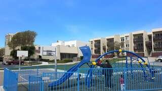 Buchanan Park Apartments exterior highlighting a family-friendly residential community with playground, open green space, and surrounding apartment buildings.