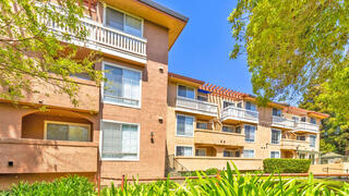 Casa Adobe Apartments exterior view of a three-story residential community with balconies, stucco exterior, and landscaped grounds.