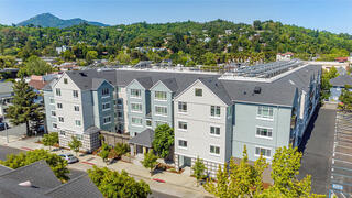 Centertown exterior features a contemporary multi-story apartment building by EAH Housing with parking underneath and rows of balconies overlooking a landscaped neighborhood.