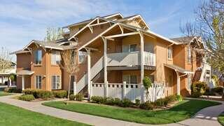 Cochrane Village Apartments, EAH Housing – Two-story residential buildings with balconies and shaded landscaping surrounded by trees and greenery.