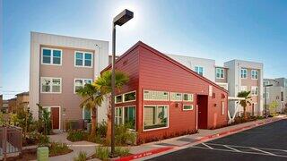 Cornerstone at Japantown, EAH Housing. Modern residential community with colorful townhomes, palm trees, and landscaped sidewalks.