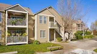 Edgewater Place, EAH Housing, exterior featuring a residential building with light green siding, large windows, and lush landscaping along a quiet neighborhood street.