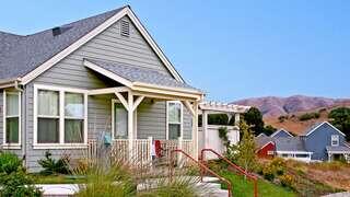 Exterior view of Point Reyes, featuring single-story cottage-style homes with porches, landscaped yards, and rolling hills in the background.
