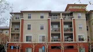Exterior view of Parkview Senior Apartments, featuring a multi-story building with balconies, columns, and accessible parking in front.
