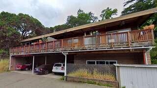 Live Oak features a small elevated residential structure with a deck on a hillside surrounded by trees in a natural setting