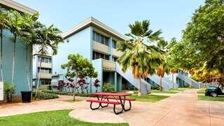 Kukui Gardens features a three story affordable housing community by EAH Housing with light blue exterior, open stairways, palm trees, and shared courtyard spaces