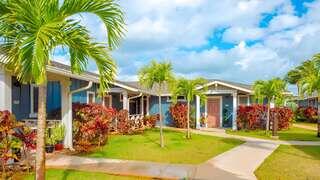 Kanikō‘ō features a single story affordable housing community by EAH Housing with plantation style homes, bright colors, and landscaped pathways in a Hawaii setting