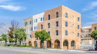 Agave exterior of a modern four-story apartment community with arched windows and active street-level entrance.