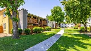 Exterior view of Summer Park Apartments, with two-story buildings, balconies, and a central landscaped courtyard with walking paths.