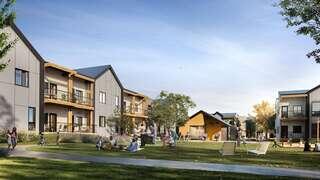 A modern residential complex with multiple buildings surrounding a green space, where people are socializing and enjoying outdoor activities.