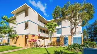Kalani Gardens features a three story affordable housing community by EAH Housing with light exterior, balconies, and tropical landscaping in a lush Hawaii setting