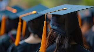 Graduates in caps with orange tassels gather, celebrating a milestone, surrounded by a soft, blurred background of nature.