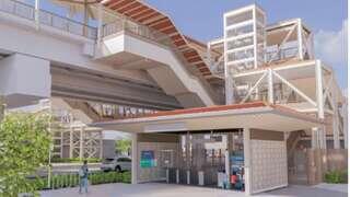 A modern transit station features a distinct architectural design with elevated walkways, ticket access, and surrounding greenery.