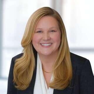 Laura Hall, President and CEO of EAH Housing, smiling in a navy blazer with pearl necklace.
