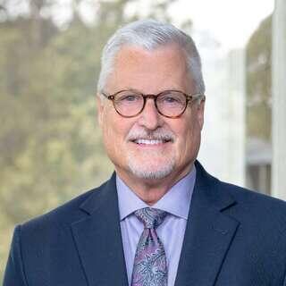 Duane Hopkins, Chief Financial Officer at EAH Housing, smiling in a navy blazer and paisley tie.