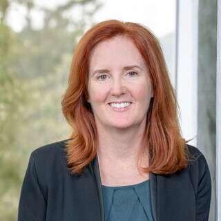 Karen Belanger, Senior Vice President of Human Resources at EAH Housing, smiling in a dark blazer with red hair.