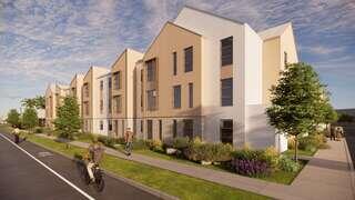 Modern townhouses with a clean design line a sidewalk, surrounded by greenery. Bicyclists and pedestrians enjoy a pleasant day.