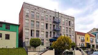Casa Rampart Apartments, EAH Housing. Historic four-story brick apartment building with decorative arched windows and a blue exterior fire escape along the front facade.