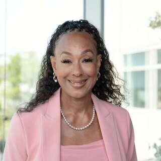 Kasey D. Archey, Senior Vice President of Real Estate Management at EAH Housing, smiling in a pink blazer with a pearl necklace.