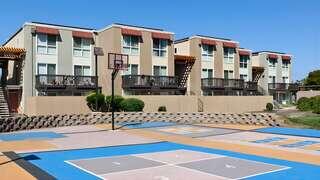 Crescent Park Apartments exterior features multi-story apartment community by EAH Housing with balconies and a shared outdoor recreation area featuring courts and seating.