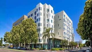 Delmas Park features a mid rise affordable housing community by EAH Housing with a modern exterior, large windows, and street level entrance in an urban neighborhood