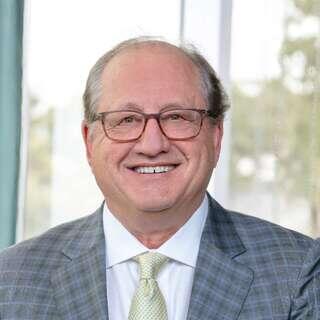 David Egan, Senior Vice President of Real Estate Development and Construction at EAH Housing, smiling in a gray plaid blazer with glasses.