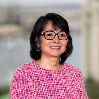 Marian Gushiken, Vice President of Real Estate Development at EAH Housing, smiling in a pink tweed top with glasses.