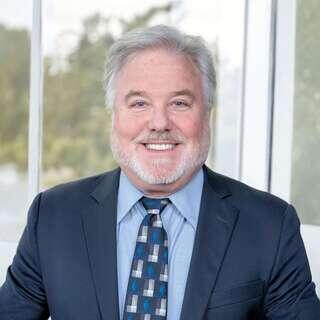 David Harris, Vice President of Risk Management at EAH Housing, smiling in a navy blazer and blue patterned tie.
