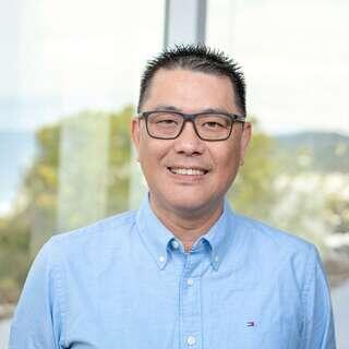 Jiano Ma, Vice President of Information Technology at EAH Housing, smiling in a light blue shirt with glasses.