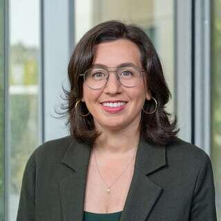 Bianca Neumann, Vice President of Business Development at EAH Housing, smiling in an olive blazer with round glasses.