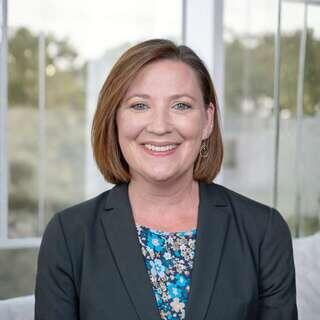 Anna Gwyn Simpson, Vice President of Resident Services at EAH Housing, smiling in a dark blazer with a floral top.