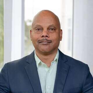 Karim Sultan, Vice President of Operations and Corporate Governance at EAH Housing, smiling in a navy blazer and light green shirt.
