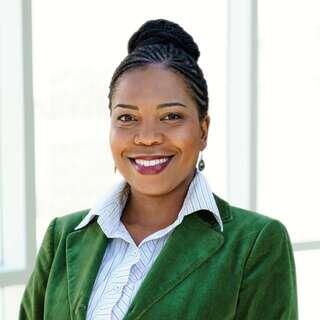 Denice Wint, Vice President of Real Estate Development at EAH Housing, smiling in a green blazer with braided updo.