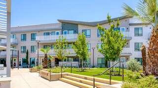 Imagine Village II features a mid rise affordable housing community by EAH Housing with a modern exterior, balconies, and landscaped open space in an urban neighborhood