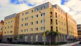 JW Apartments features a four story affordable housing community by EAH Housing with stucco exterior, balconies, and arched ground level design along a city street