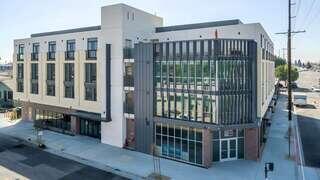 Exterior view of Pointe on Vermont, a modern multi-story building with white and gray facade, large windows, and street-level commercial space.
