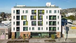 Exterior view of Pointe on La Brea, a modern multi-story building with white and green facade, balconies, and a street-facing entrance.