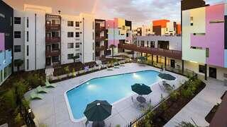 Exterior courtyard view of Paseo Senter, a colorful modern community with a central pool, lounge seating, and connecting walkways.