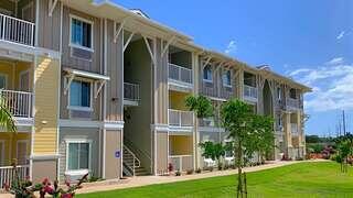 Kenolio Apartments features a three story affordable housing community by EAH Housing with colorful exterior, balconies, and landscaped lawn in a lush Hawaii setting