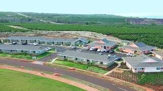 Aerial view of charming residential buildings surrounded by greenery and a serene landscape, with parked cars and well-maintained grounds.