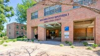 A brick building with large windows and a welcoming entrance, featuring landscaping and signage for "New Directions Sepulveda I."